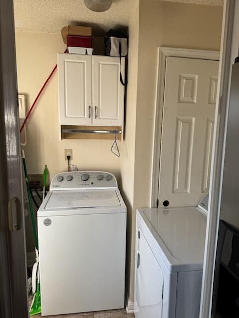 laundry room featuring cabinet space, a textured ceiling, and separate washer and dryer