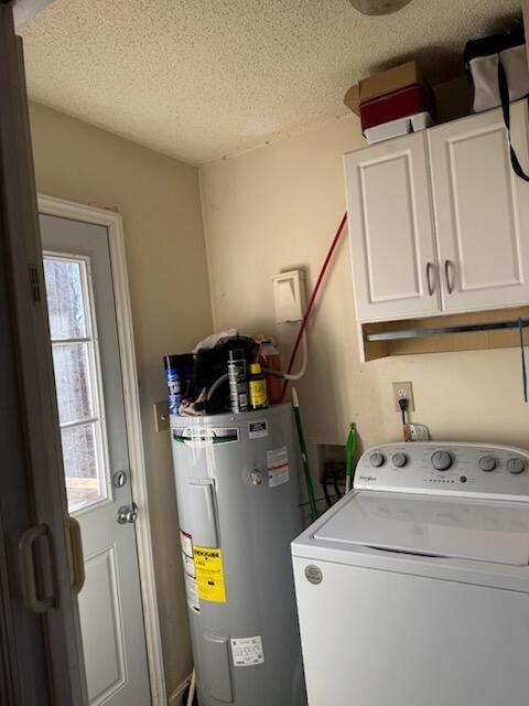 laundry area featuring washer / dryer, water heater, cabinet space, and a textured ceiling