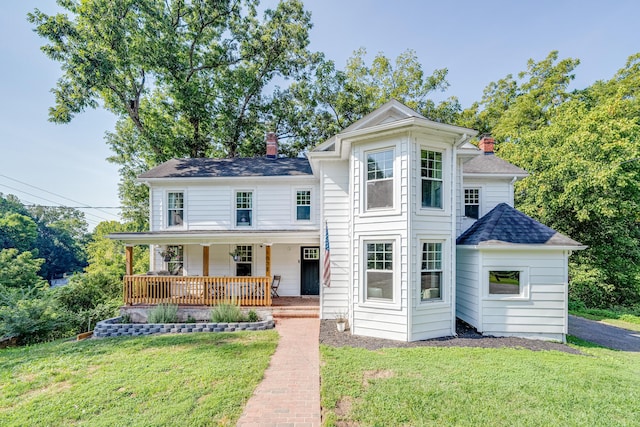 view of front of house with a chimney, a front lawn, a porch, and roof with shingles