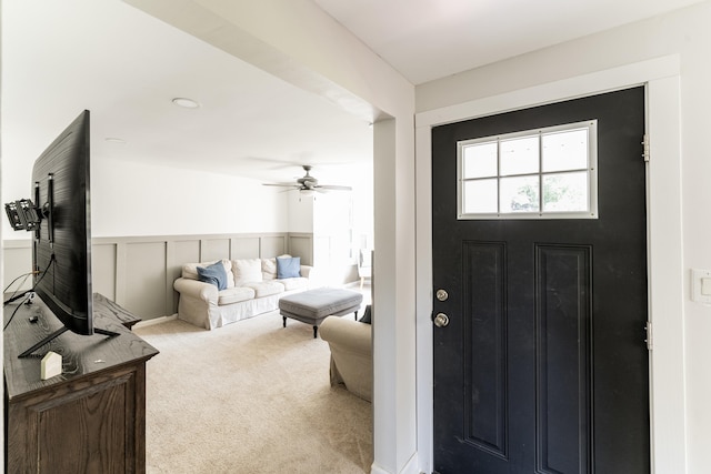 carpeted entrance foyer featuring a decorative wall and wainscoting