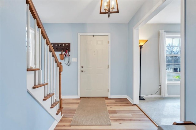 entrance foyer featuring stairway, an inviting chandelier, light wood-style flooring, and baseboards