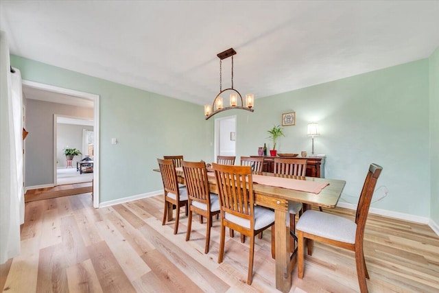 dining space with light wood-type flooring and baseboards