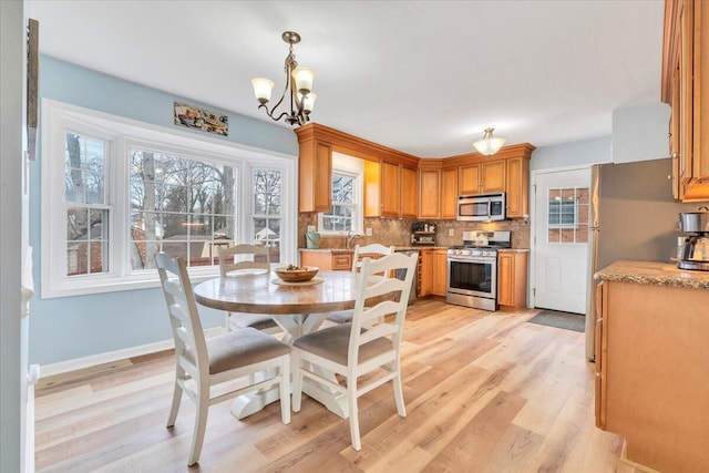 dining space with light wood-type flooring, an inviting chandelier, and baseboards