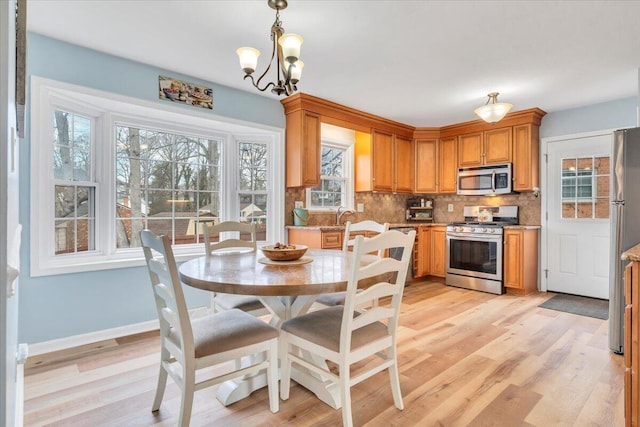 dining room with light wood-type flooring, baseboards, and a chandelier