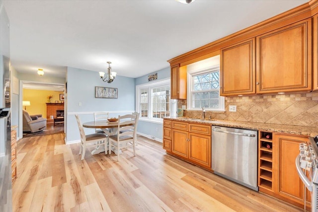 kitchen with light wood-style flooring, decorative backsplash, appliances with stainless steel finishes, brown cabinetry, and a sink