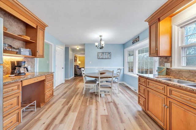 kitchen with tasteful backsplash, light wood-style flooring, brown cabinets, and built in study area