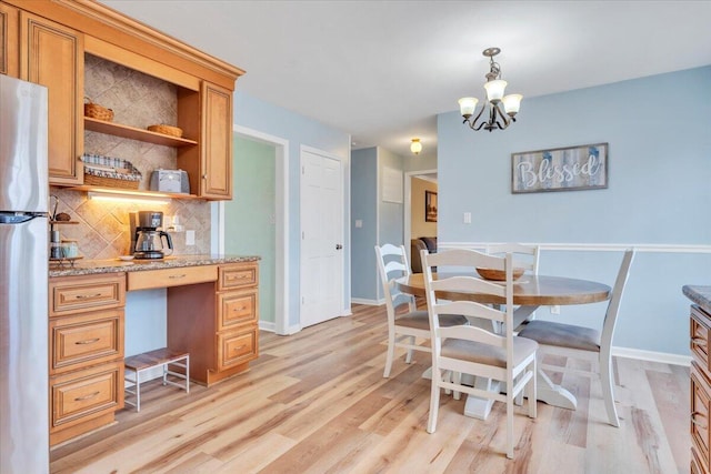 dining space with built in desk, an inviting chandelier, light wood-style flooring, and baseboards