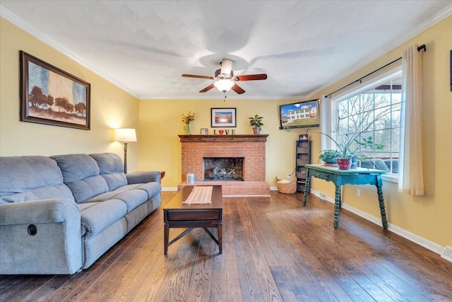 living area featuring baseboards, dark wood finished floors, ceiling fan, ornamental molding, and a fireplace