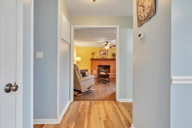 hall with light wood-style flooring and baseboards