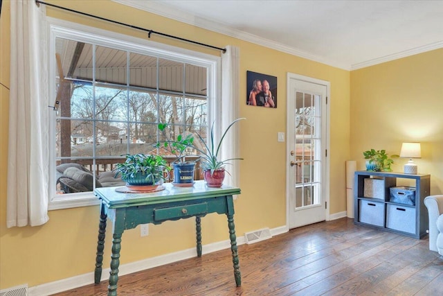 doorway to outside with ornamental molding, wood-type flooring, visible vents, and baseboards