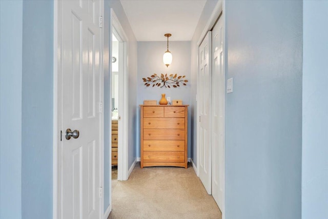 hall with baseboards and light colored carpet