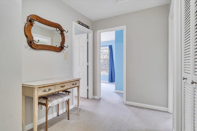 corridor with baseboards and light colored carpet