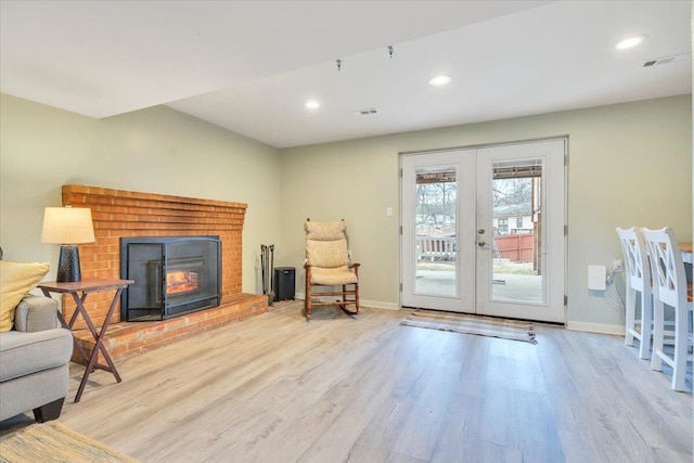 sitting room featuring a fireplace, baseboards, wood finished floors, and french doors