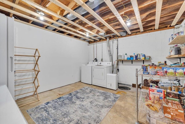 unfinished basement featuring concrete block wall and independent washer and dryer