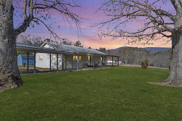 back of house with a mountain view, metal roof, a lawn, and a patio