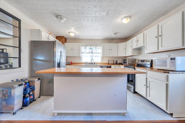 kitchen with white cabinets, butcher block counters, and stainless steel appliances