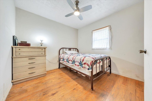 bedroom with a textured ceiling, baseboards, a ceiling fan, and light wood-style floors