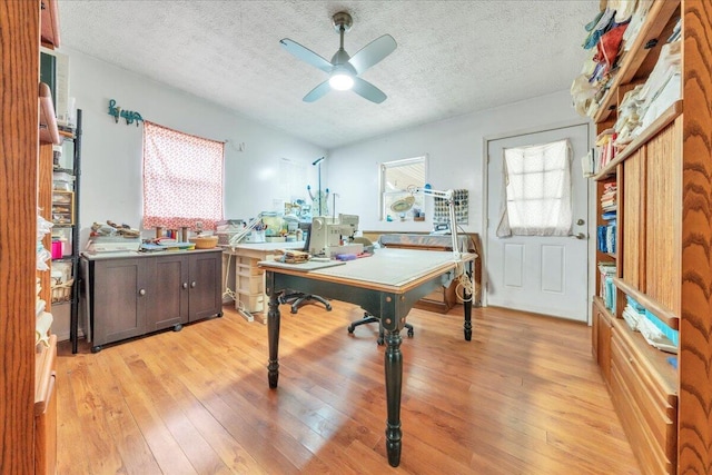 home office featuring light wood-style flooring, a ceiling fan, and a textured ceiling