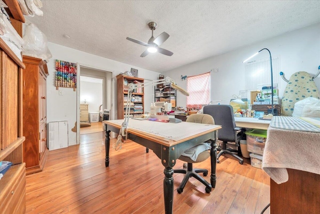 office area featuring light wood-style floors, ceiling fan, and a textured ceiling