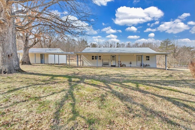 back of property featuring metal roof and a yard