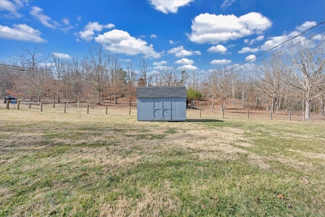 view of yard featuring a shed, a rural view, an outdoor structure, and fence