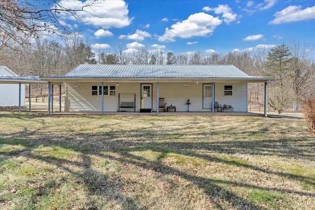 view of front of home featuring metal roof, a front lawn, and a patio