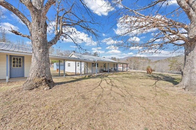 rear view of house with metal roof, a lawn, and a mountain view