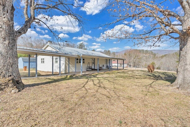 back of property featuring a patio area, metal roof, a carport, and a yard