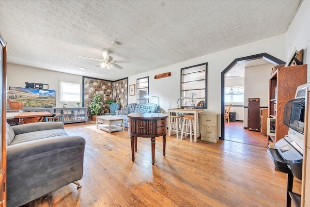 home office with arched walkways, ceiling fan, a textured ceiling, and hardwood / wood-style flooring