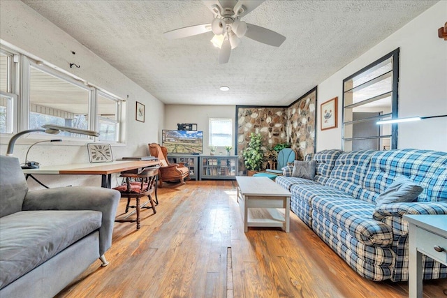 living area featuring wood-type flooring, a ceiling fan, and a textured ceiling