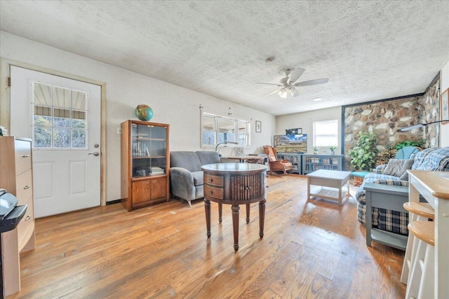 living room featuring a ceiling fan, a textured ceiling, and wood finished floors