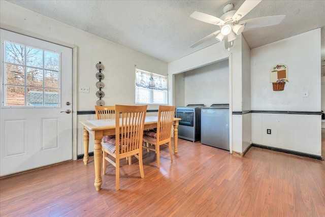 dining area with light wood-style floors, washing machine and dryer, ceiling fan, and a textured ceiling