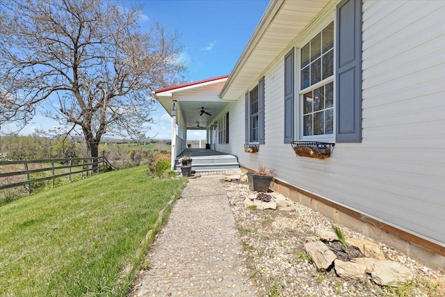 doorway to property featuring a lawn, a porch, ceiling fan, and fence