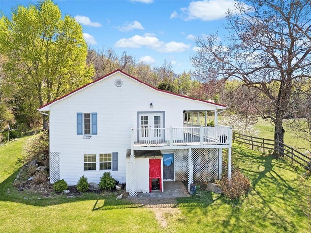 rear view of property featuring a lawn, fence, a patio, and french doors