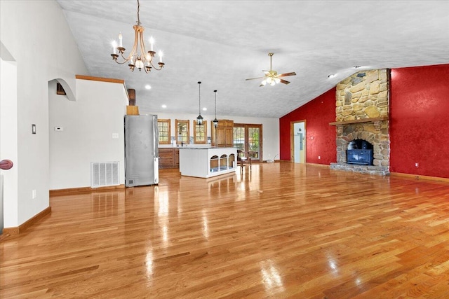 unfurnished living room with lofted ceiling, ceiling fan with notable chandelier, visible vents, and light wood-type flooring