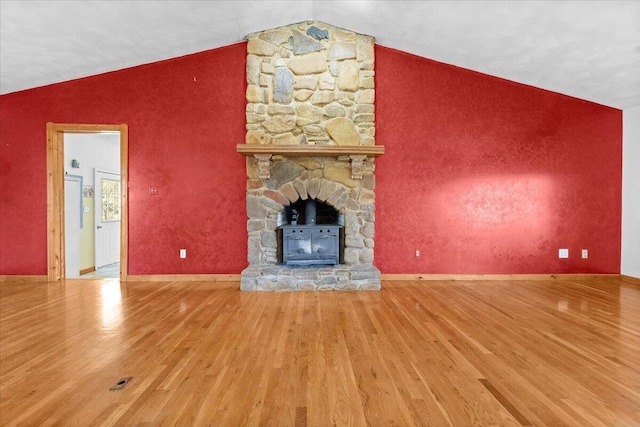 unfurnished living room featuring a fireplace, vaulted ceiling, and wood finished floors