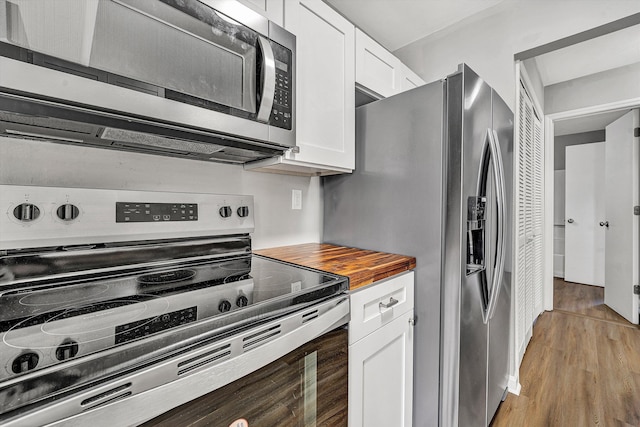 kitchen featuring white cabinets, light wood-style floors, appliances with stainless steel finishes, and wooden counters