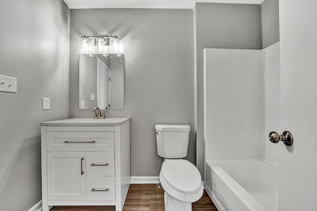 bathroom featuring baseboards, toilet, wood finished floors, and vanity