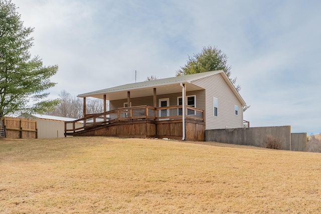 rear view of property featuring a lawn, a deck, and fence