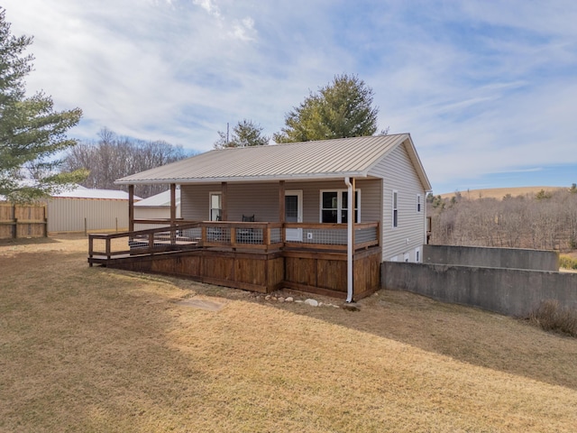 back of house with metal roof, a lawn, and fence