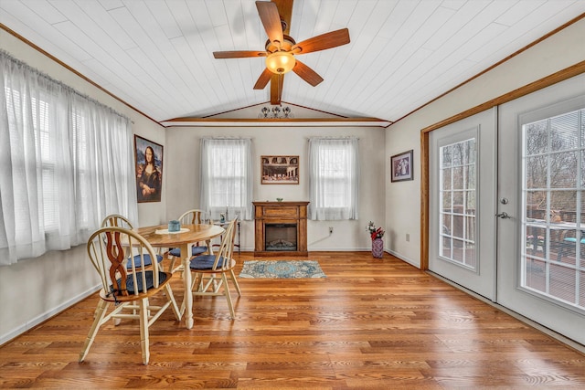 dining space with french doors, a fireplace, vaulted ceiling with beams, and wood finished floors