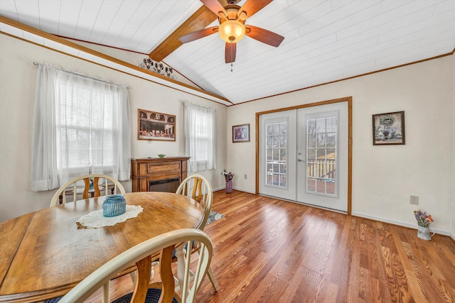 dining area featuring lofted ceiling with beams, wood finished floors, baseboards, french doors, and ornamental molding