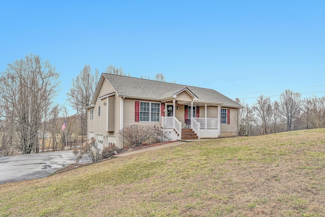 ranch-style home featuring driveway, a garage, roof with shingles, covered porch, and a front yard