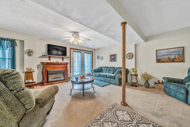 living area with carpet, a glass covered fireplace, and a ceiling fan