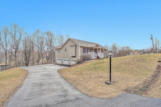 view of front of property featuring driveway, covered porch, a garage, and a front yard