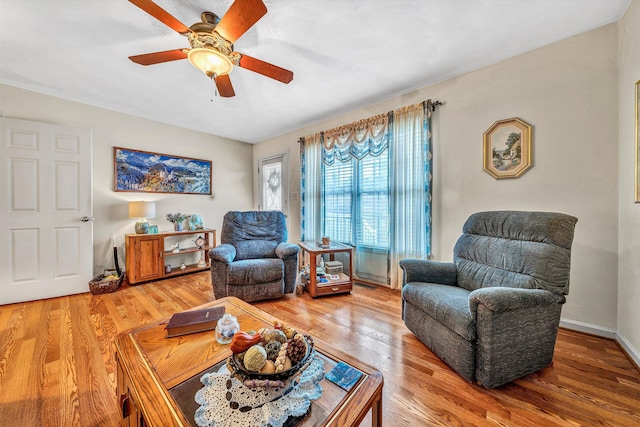 living area featuring light wood-style flooring, baseboards, and a ceiling fan