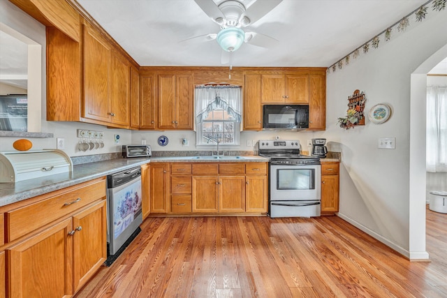 kitchen with appliances with stainless steel finishes, light wood-style floors, brown cabinets, and a sink