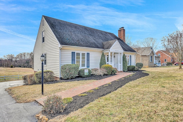 new england style home with a chimney, fence, a front lawn, and roof with shingles