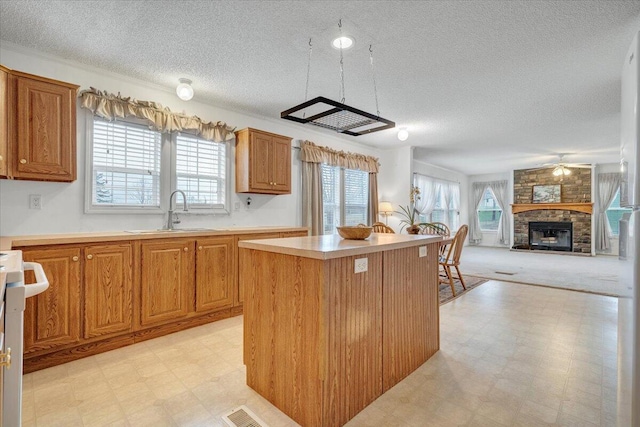 kitchen featuring stove, light floors, visible vents, a center island, and a sink