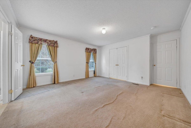 unfurnished bedroom featuring baseboards, carpet, a textured ceiling, and crown molding